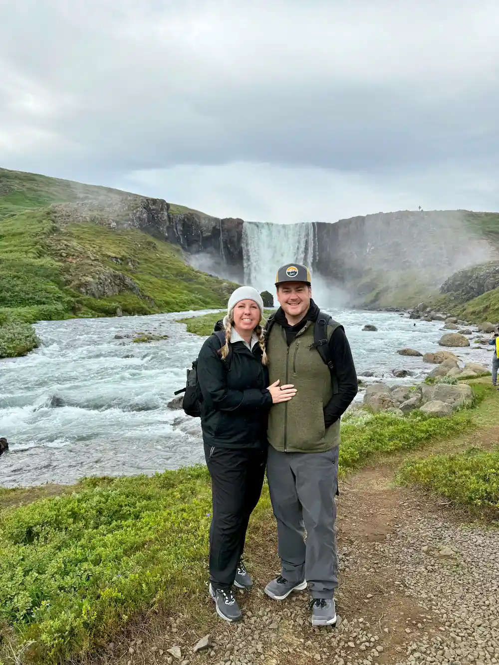 Couple posing before large waterfall and river
