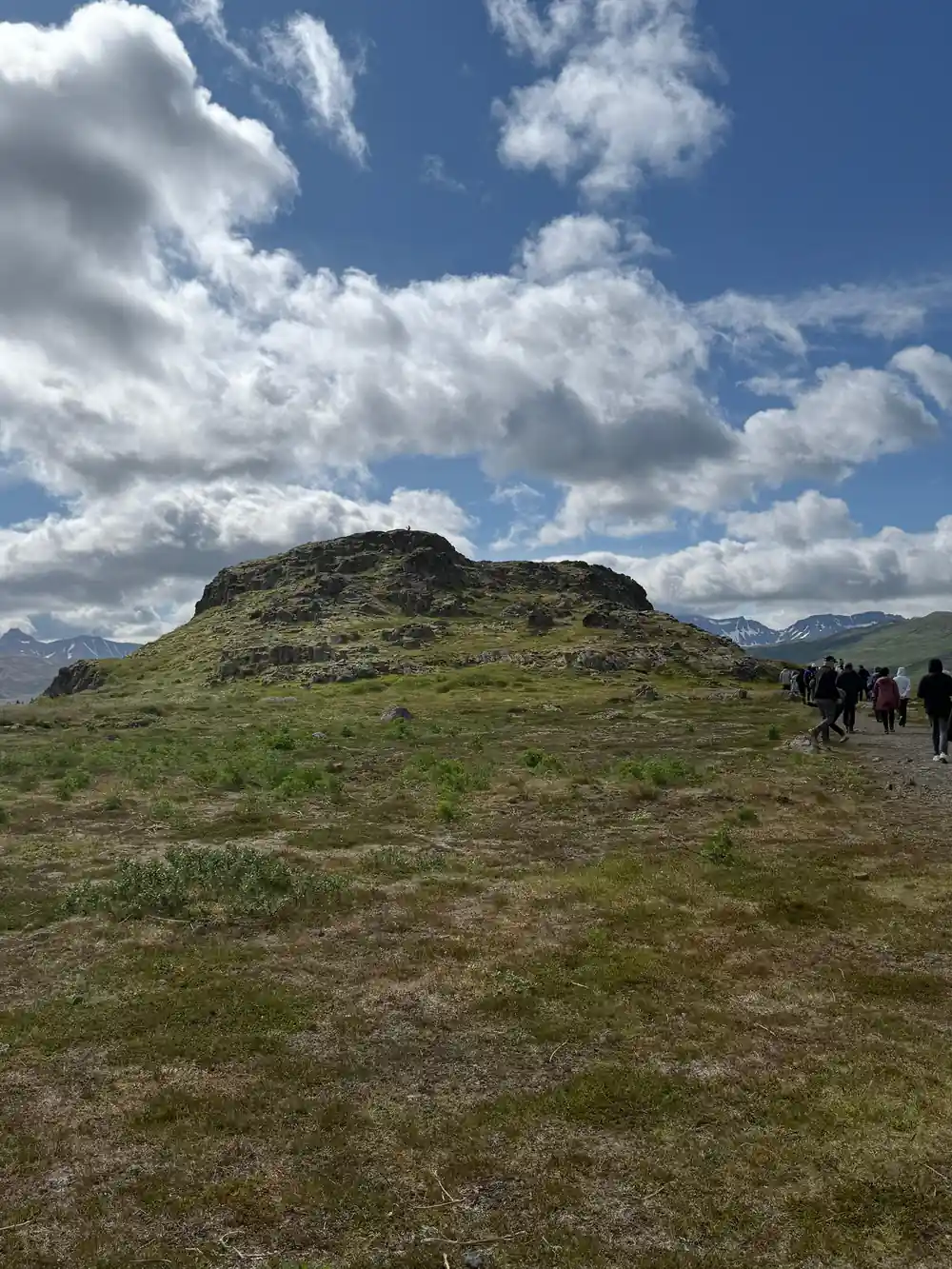 Green hillside with ancient stone structure and distant mountains