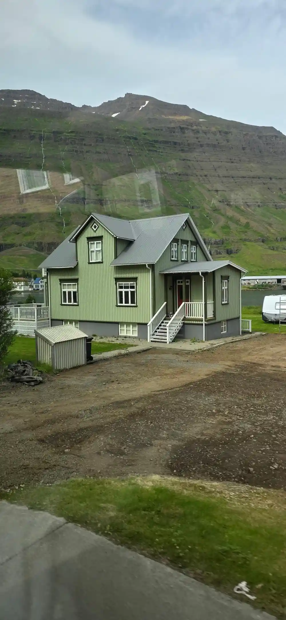 Green house on hillside at base of mountain
