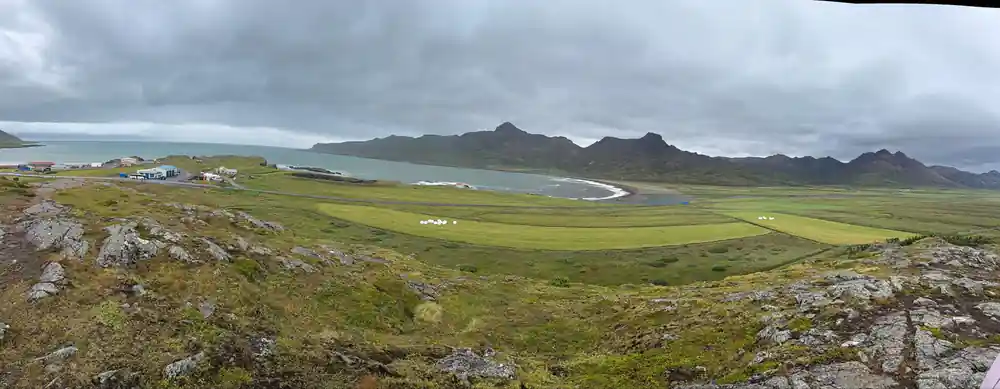 Green valley with mountains and coastal inlet beyond