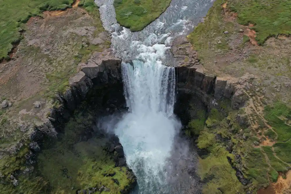 Narrow waterfall dropping into mossy gorge from above