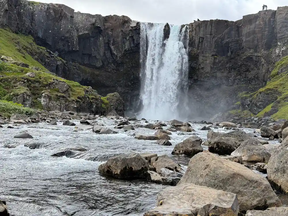 Powerful waterfall cascading between dark rock cliffs into river