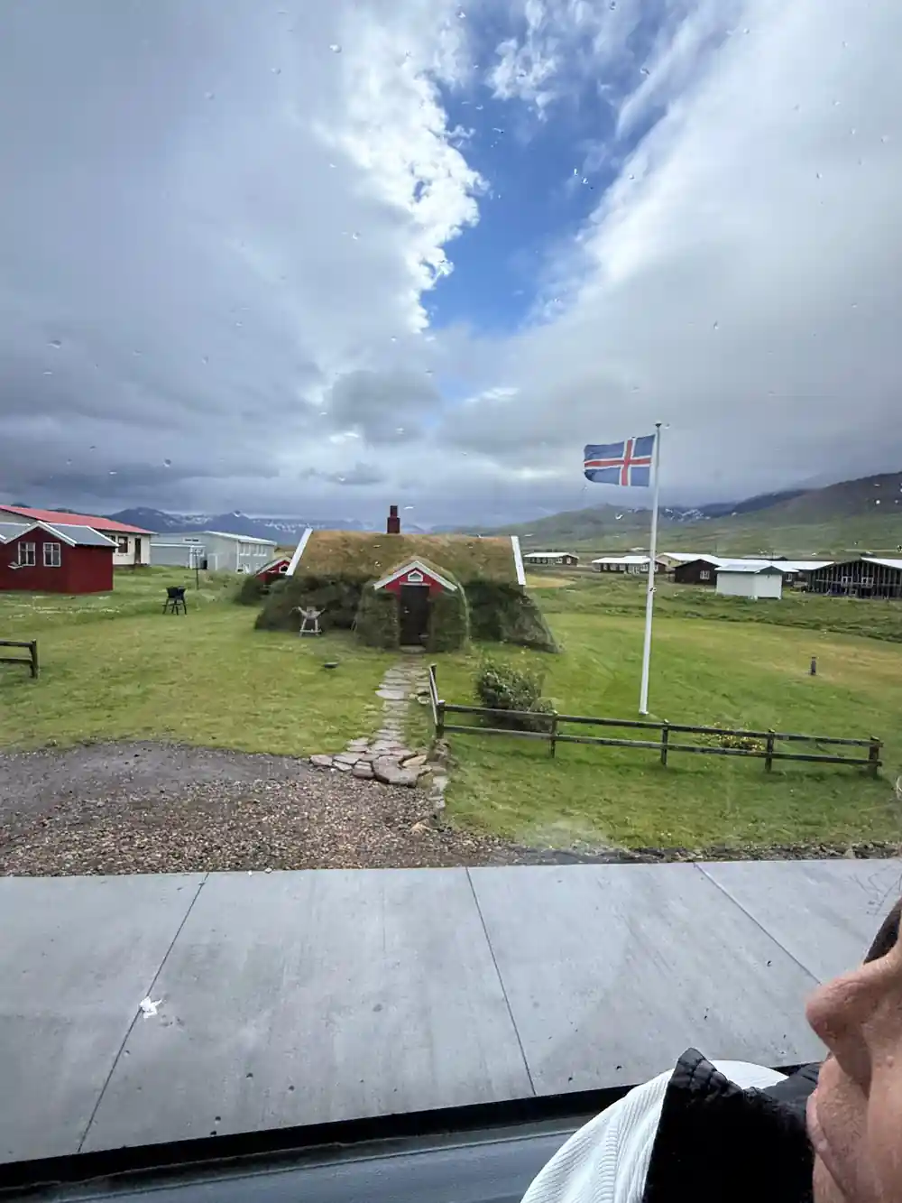 Turf-roofed house with flag in green field
