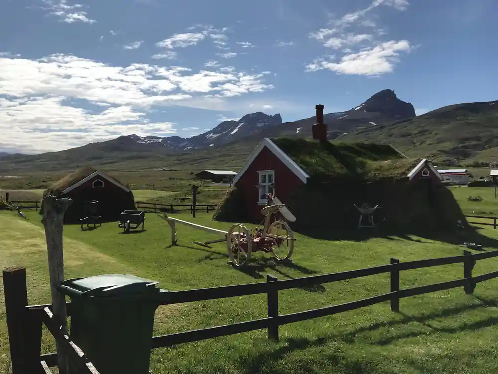 Turf-roofed houses with mountains in grassy valley