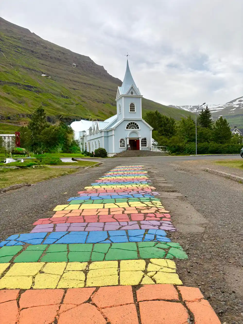 White church with rainbow painted path and mountain background
