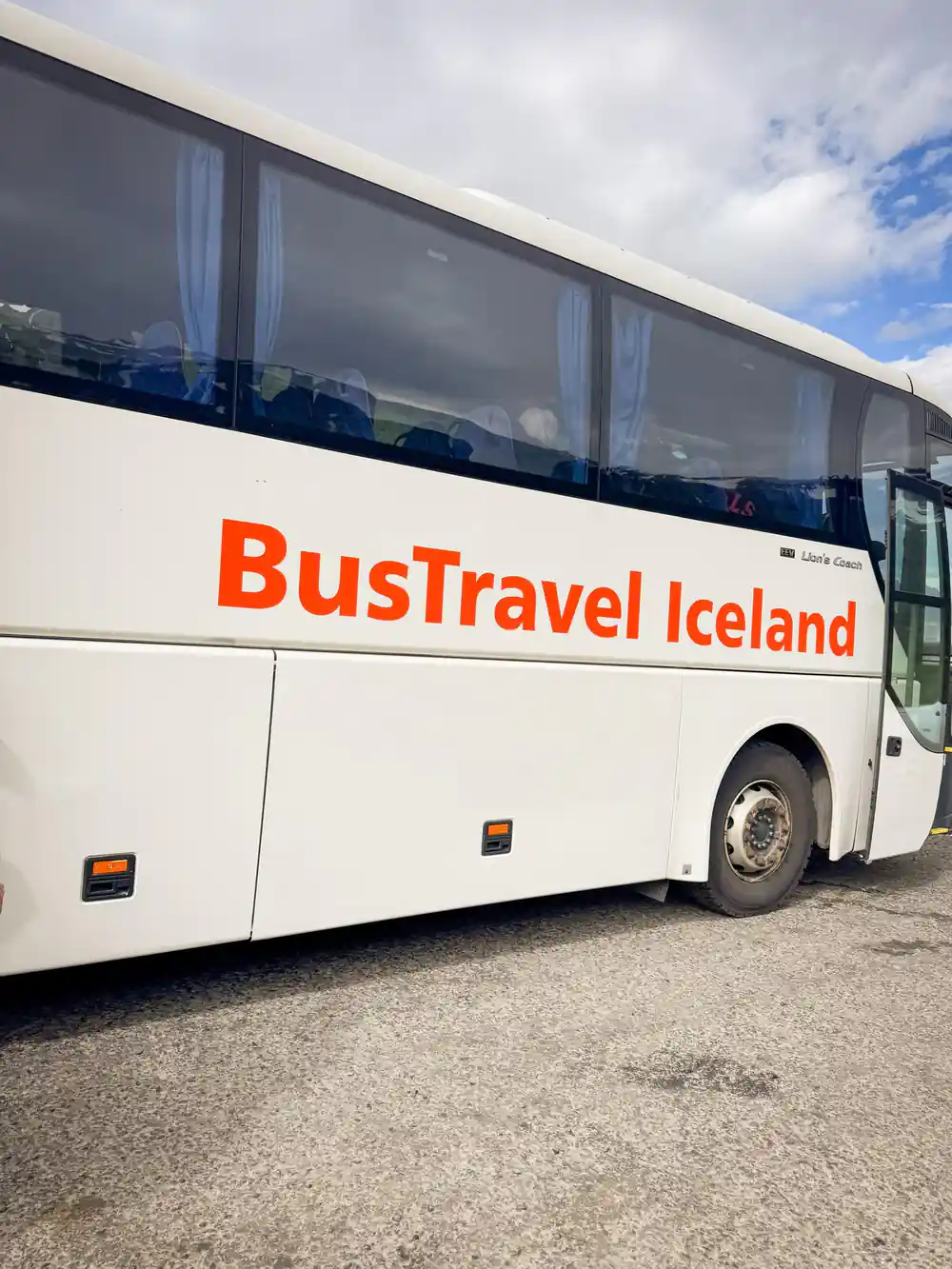 White coach bus with BusTravel Iceland branding parked outdoors